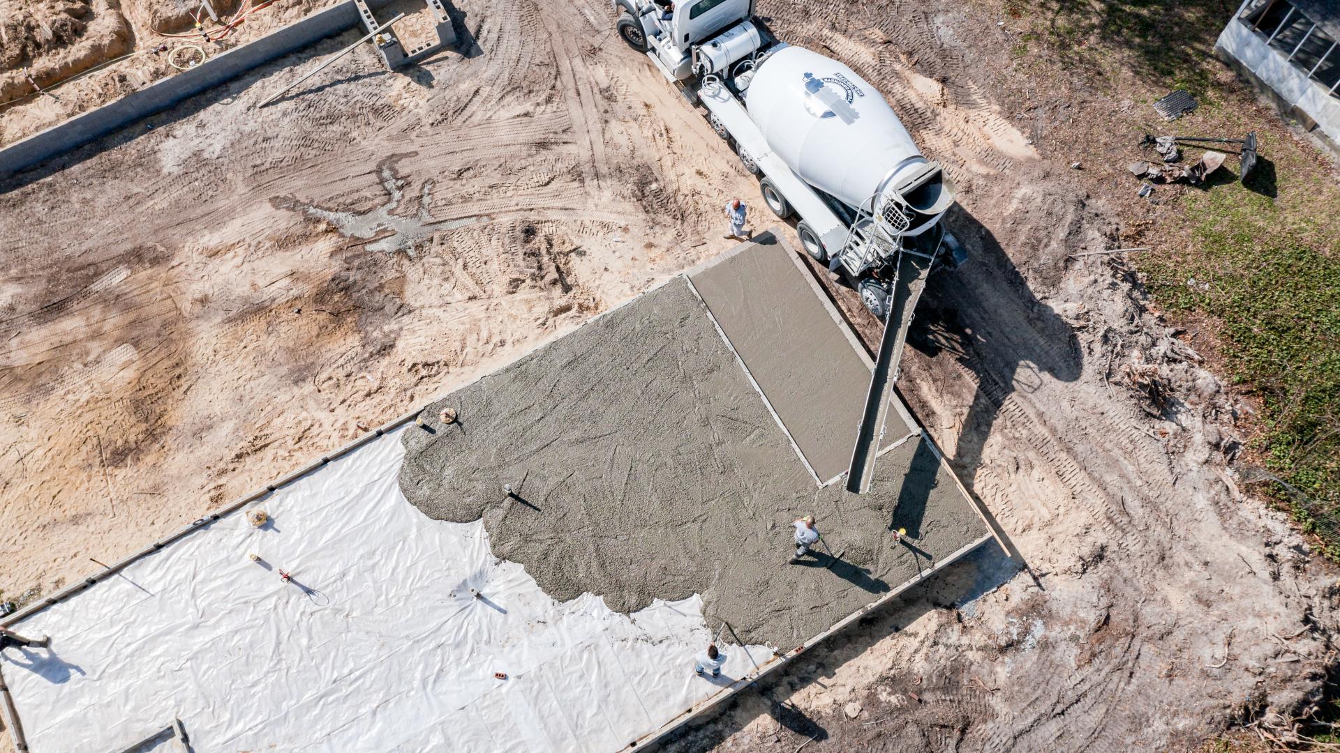 Transmikserden döşeme kalıbına taze beton dökülüyor; ekip betonu yayıyor
